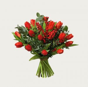 Röda tulpaner, röd ilex och eucalyptus. Överraska med ett blomsterbud från Interflora!