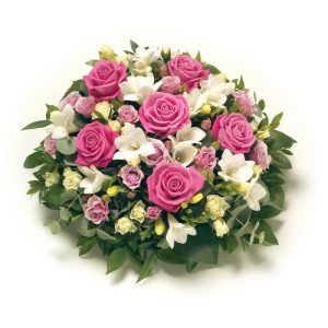 Fantastiskt vacker, rund blomsterkudde, med snittblommor i rosa och vitt mot gröna blad. På bilden en kudde med rosa rosor, vita fresior, vita prärieklockor. 