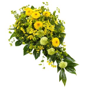 Liggande gul sorgdekoration, med germini, santini och nejlikor och så gröna blad förstås. 