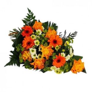 Liggande begravningsbukett i orange, vitt och grönt. Här orange rosor och gerbera, vita krysantemum och gröna blad (blomsorter kan variera något)