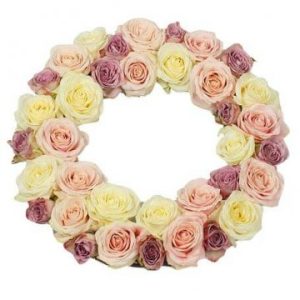 Rund begravningskrans, fylld med ljusrosa, ljusgula/vita och mörkrosa (lite åt lila) rosor. Endast blommor, inget grönt.