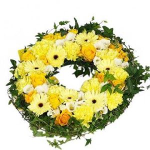 Underbar, rund begravningskrans med grön murgröna i basen. Längs hela kransen: blandade gula, vita och några ljust orange blommor. Blomsorter kan variera något, beroende på tillgång i den butik som får hand om ditt blomsterbud.