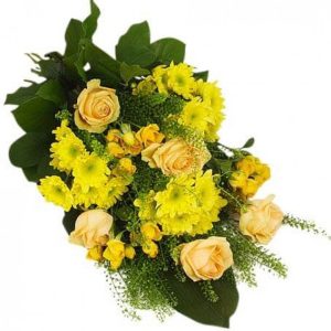 Begravningsbukett med gula blommor mot gröna blad. Liggande. På bilden rosor, gerbera och krysantemum (variationer av blomsorter kan förekomma i olika butiker)